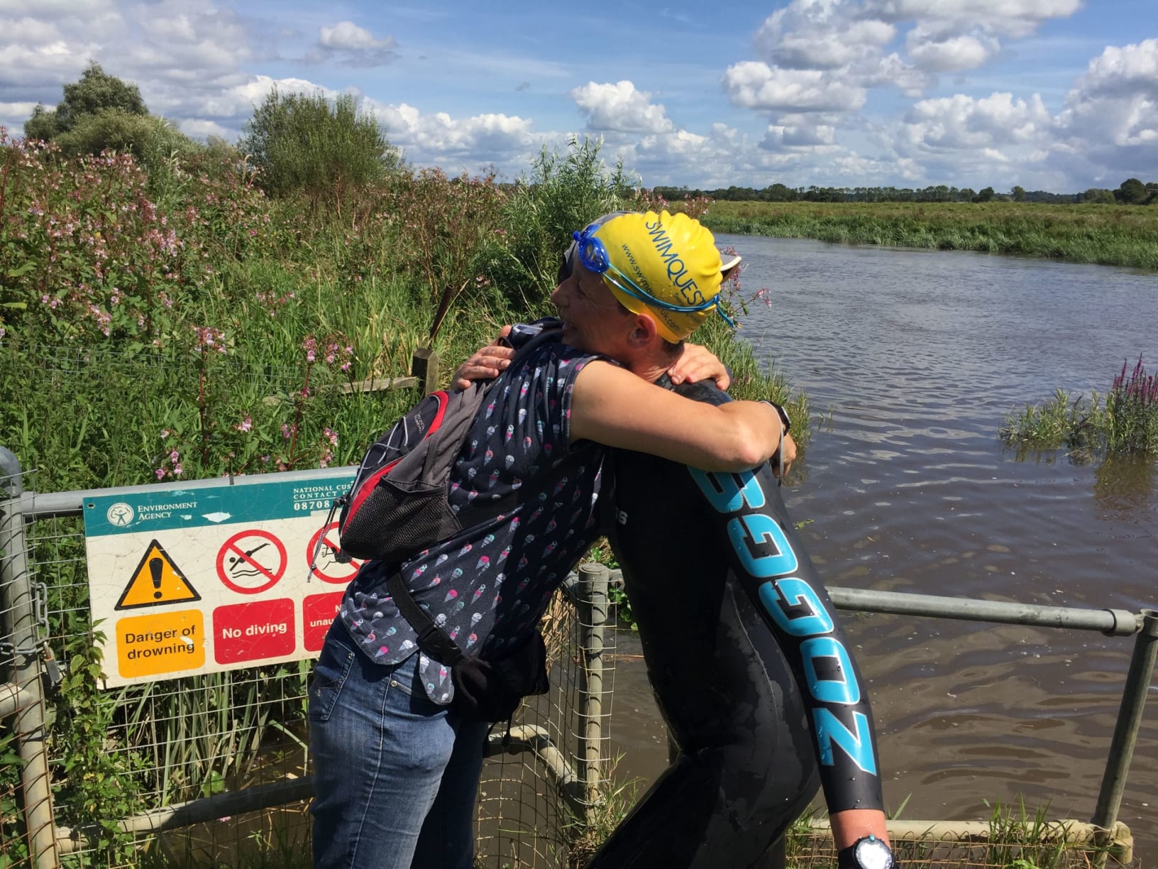 Swimmer embracing a friend after river swim